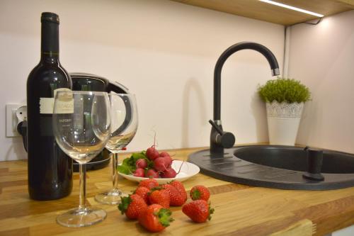 a counter with a bottle of wine and a plate of strawberries at Tylawa - Domki w Beskidzie Niskim in Tylawa