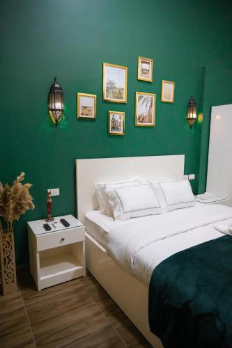 a bedroom with a white bed and a green wall at Hathor House in Cairo