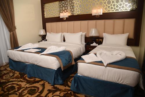 two beds in a hotel room with towels on them at فندق الاندلس الماسي - Alandalus Diamond Hotel in Al Madinah