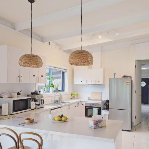 a kitchen with white cabinets and stainless steel appliances at Cosy Brick Beachouse - ALL INCLUDED in Inverloch
