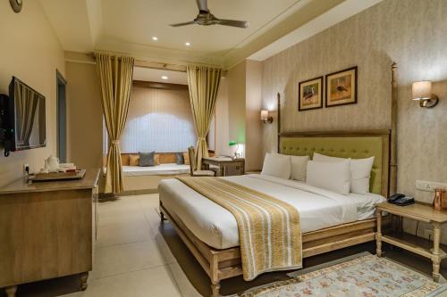 ein Hotelzimmer mit einem großen Bett und einem TV in der Unterkunft Rupal Residency in Jaisalmer