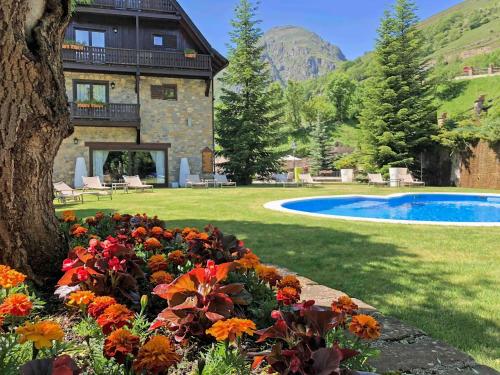 a house with a yard with a pool and flowers at Hotel de Tredós Baqueira, Affiliated by Meliá in Tredós