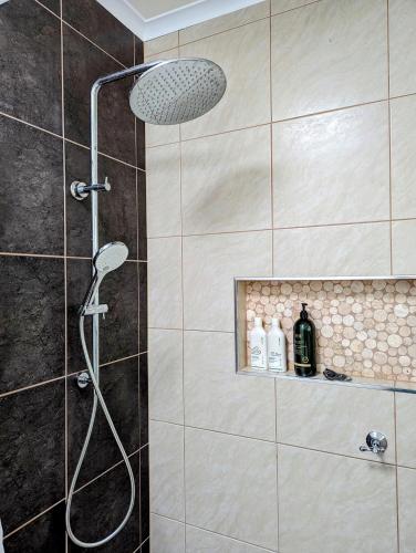 a shower with a shower head in a bathroom at Cosy Brick Beachouse - ALL INCLUDED in Inverloch