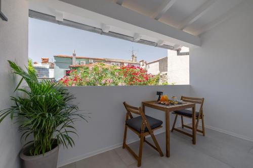 uma varanda com mesa, cadeiras e flores em B&B Miracolo di Mare Golden House em Piran