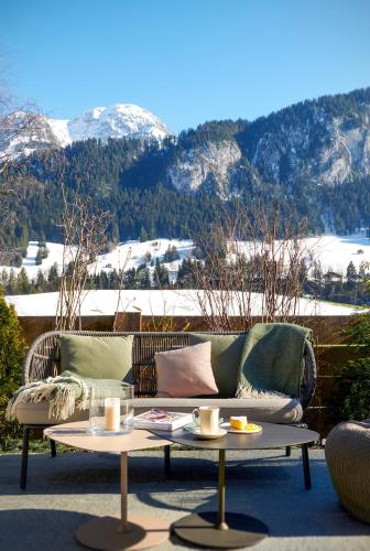 a couch sitting on a patio with two coffee tables at Maison d'hôtes Ermitage in Chateau-d'Oex