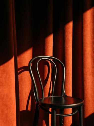 a black chair sitting in front of orange curtains at WELTWIEN Luxury Art Apartments & Free Parking in Vienna