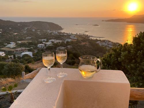 two glasses of wine sitting on a table with the sunset at VILLA NOVA Leros in Drymonas