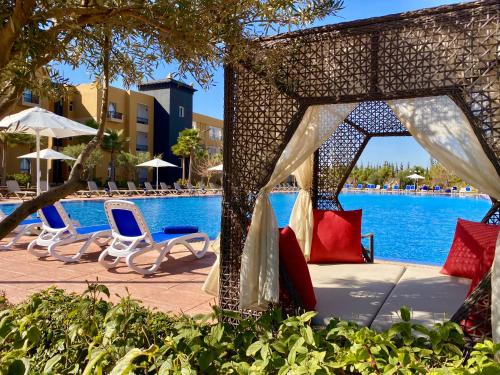 a group of chairs and umbrellas next to a pool at El Olivar Palace Marrakech All Inclusive, Aquapark & SPA in Marrakech