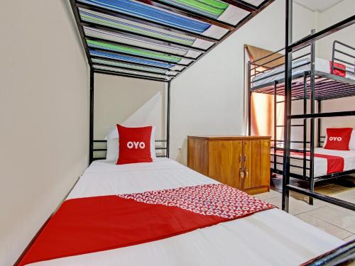 Schlafzimmer mit einem roten und weißen Bett und Etagenbetten in der Unterkunft OYO 92617 Omahku Homestay Hostel in Yogyakarta