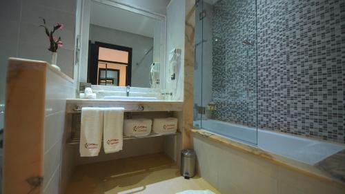 a bathroom with a tub and a sink and a mirror at El Olivar Palace Marrakech All Inclusive, Aquapark & SPA in Marrakech