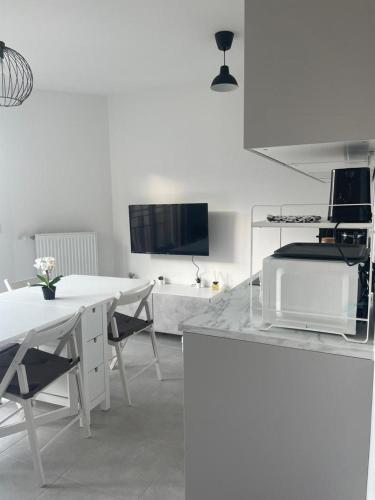 Il comprend une cuisine blanche avec une table et une télévision. dans l'établissement Cosy studio Chessy 9min Disneyland, à Chessy