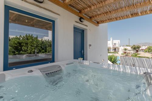 a hot tub in a room with a window at Naxian Queen Luxury Villas & Suites in Agia Anna Naxos
