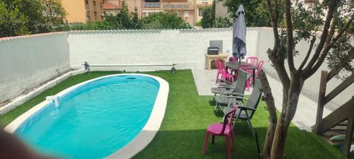 uma piscina com cadeiras cor-de-rosa e um guarda-sol em Location maison avec piscine privée. em Agde