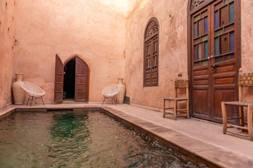 a house with a swimming pool with two chairs and doors at Riad Ben Youssef in Marrakesh
