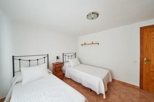 two beds in a room with white walls at Casa Lalu in San José
