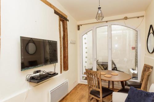 un salon avec une table et une télévision dans l'établissement Charming with Terrace in the Heart of the 17th, à Paris