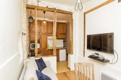 un salon avec un canapé blanc et une télévision dans l'établissement Charming with Terrace in the Heart of the 17th, à Paris