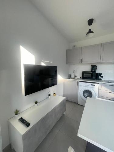 a white kitchen with a tv on the wall at Cosy studio Chessy 9min Disneyland in Chessy