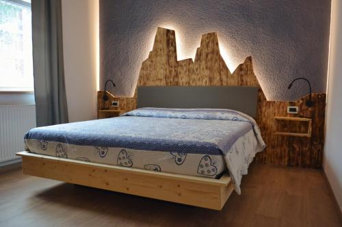 a bedroom with a bed with a wooden headboard at Hotel Garnì Nès Crépes in Pozza di Fassa