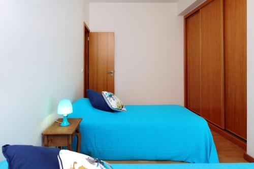 a bedroom with a blue bed and a wooden door at O búzio in Albufeira