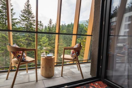 a balcony with two chairs and a table in front of a window at Hotel Nomad in Bjelašnica