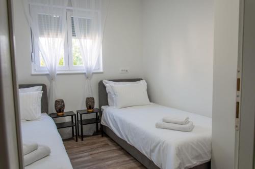 sypialnia z 2 łóżkami z białą pościelą i oknem w obiekcie Apartman Sistov w mieście Kaštela