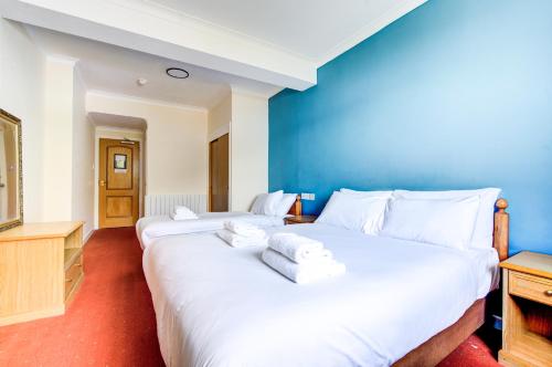 two beds in a room with a blue wall at Onich Hotel & Lochside Beach Pods in Onich