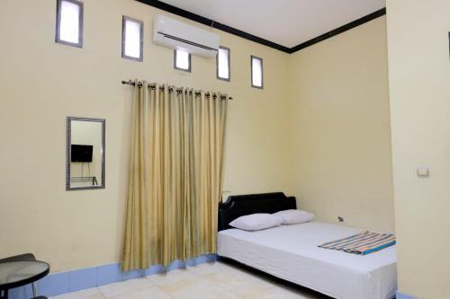 um quarto com uma cama com uma cortina e um espelho em Hotel Puri Lembang near Universitas Sulawesi Barat Majene em Lutan