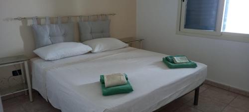 Una cama blanca con dos toallas verdes. en Villa Ipanema, en Salve