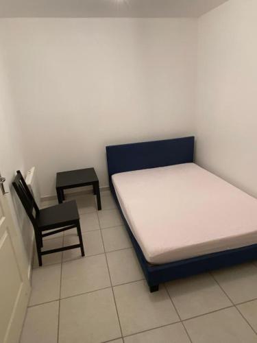 1 dormitorio pequeño con 1 cama y 1 silla en petit appartement calme en plein centre du village de ribiers, en Ribiers