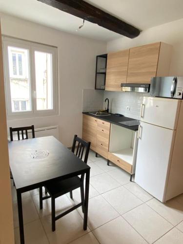 a kitchen with a table and a white refrigerator at petit appartement calme en plein centre du village de ribiers in Val Buëch-Méouge