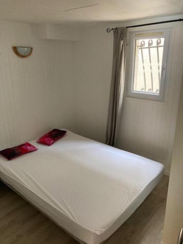 - un lit blanc dans une chambre avec fenêtre dans l'établissement L’appartement du Micocoulier, à Salon-de-Provence