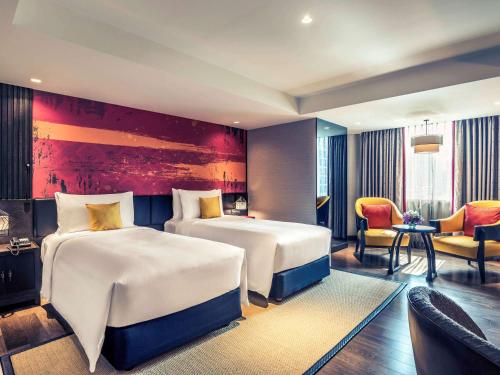 a hotel room with two beds and a couch at Mercure Bangkok Sukhumvit 11 in Bangkok