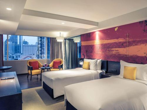 Mercure Bangkok Sukhumvit 11 في بانكوك: غرفة فندقية بسريرين وطاولة وكراسي