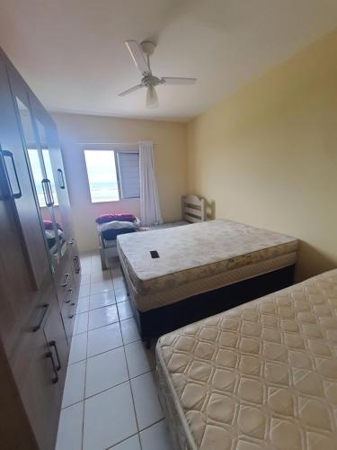 a bedroom with two beds and a ceiling fan at Apto de frente ao mar Itanhaém in Itanhaém