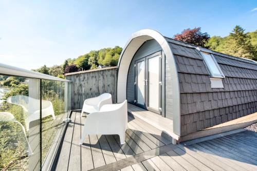 a tiny house with a pitched roof and white chairs on a deck at Onich Hotel & Lochside Beach Pods in Onich