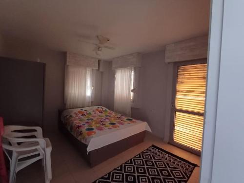 a bedroom with a bed and a chair and a window at SUNSET-Denize sıfır konumda, eşyalı yazlık in Seferihisar