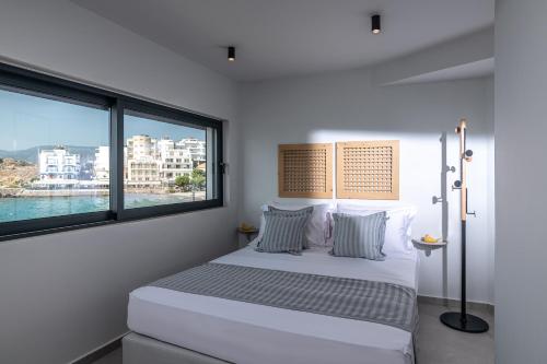 Schlafzimmer mit einem Bett und einem großen Fenster in der Unterkunft Sea Front Salty Sea Suites Estate in Agios Nikolaos