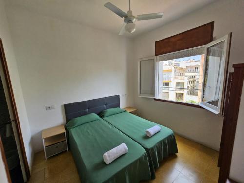a bedroom with a green bed and a window at Hostal Cruz in Tossa de Mar