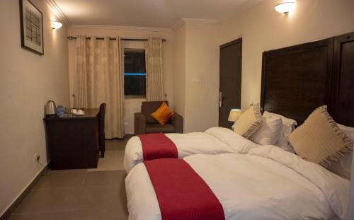 a hotel room with two beds and a chair at SSNIT GUEST HOUSE in Nima