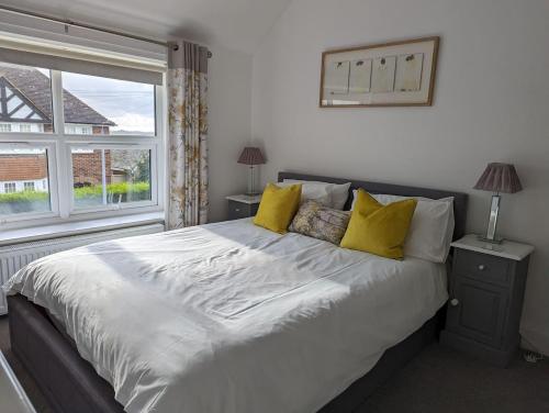 a bedroom with a large bed with yellow pillows at Cadborough Cliff Apartment in Rye