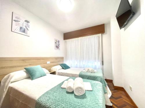 a hotel room with two beds with towels on them at Pension O Camiño Milladoiro in Amés