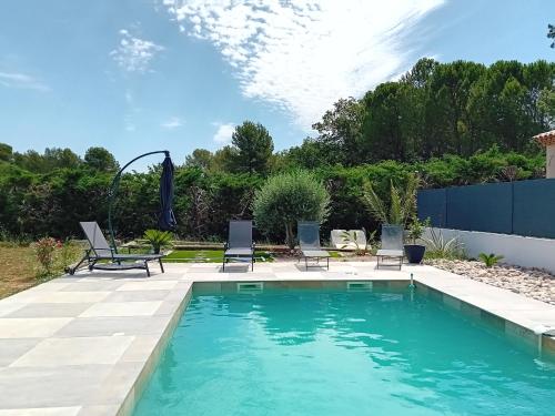 einen Pool mit zwei Stühlen und einem Tisch im Hof in der Unterkunft Villa au soleil in Trans-en-Provence