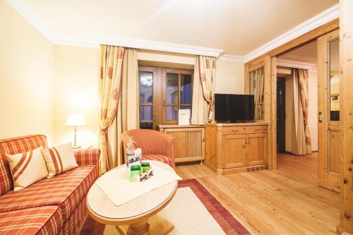 a living room with a couch and a tv at Familien- und Wellnesshotel Hanneshof in Kleinarl