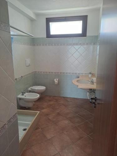 a bathroom with two toilets and a sink and a window at Fattoria Manostalla Villa Chiarelli in Balestrate