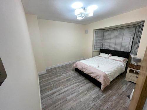 een slaapkamer met een bed en een houten vloer bij Modern 4-bedroom entire house with Garden in Uxbridge