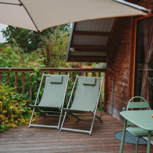 two lawn chairs and an umbrella on a deck at Domaine de la Fauvriere in Sainte-Honorine-de-Ducy