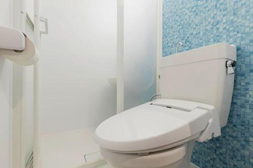 a white toilet in a bathroom with blue tiles at Mash Cafe & Bed NAGANO in Nagano