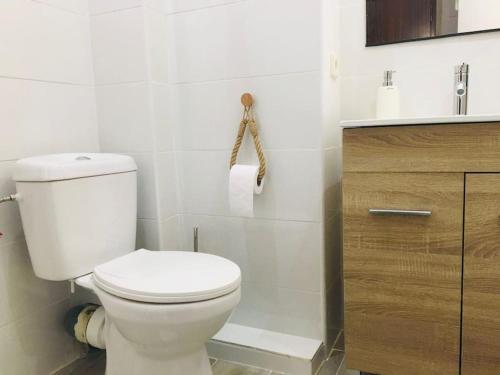 La salle de bains est pourvue de toilettes blanches et d'une armoire en bois. dans l'établissement Apartamento ABRIL en el Centro de Getafe, à Getafe