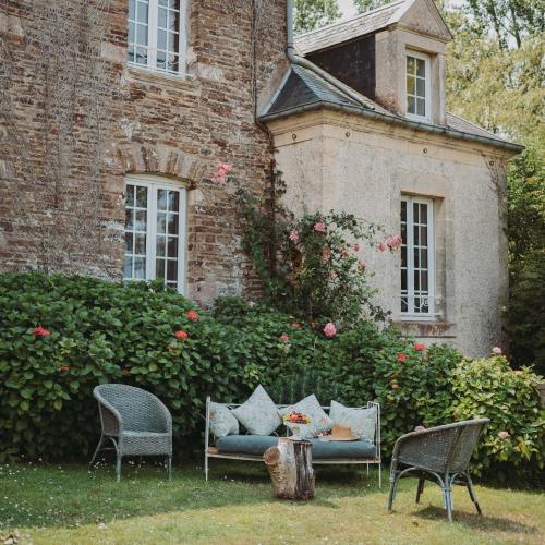a couch and two chairs in front of a building at Domaine de la Fauvriere in Sainte-Honorine-de-Ducy